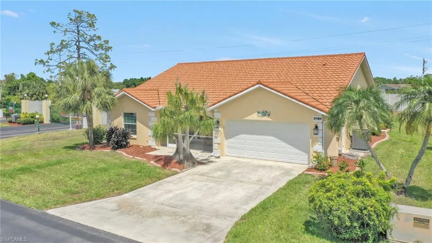 View of front of property featuring a tile roof, a front lawn, driveway, an attached garage, and stucco siding