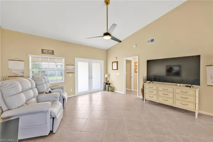 Living area with light tile patterned floors, ceiling fan, french doors, baseboards, and visible vents
