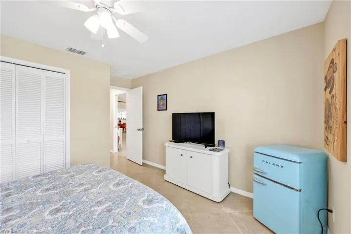 Bedroom with fridge, light tile patterned floors, ceiling fan, baseboards, and visible vents