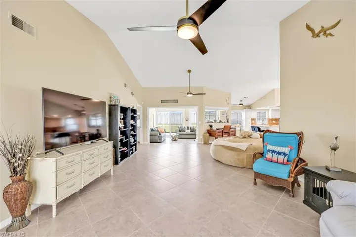 Living area with visible vents, a ceiling fan, high vaulted ceiling, and light tile patterned floors