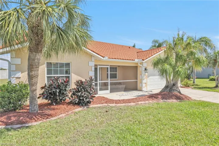 View of front of property with a tile roof, a front lawn, driveway, a garage, and stucco siding