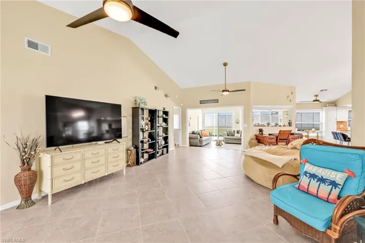 Living area featuring light tile patterned flooring, visible vents, high vaulted ceiling, and ceiling fan