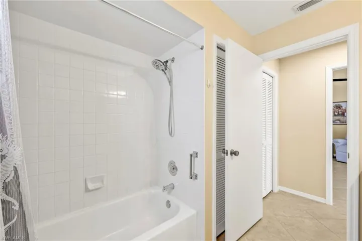 Bathroom with visible vents, tile patterned flooring, baseboards, and shower / bathtub combination with curtain