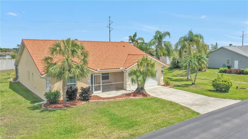 View of front facade with stucco siding, an attached garage, a tile roof, driveway, and a front yard