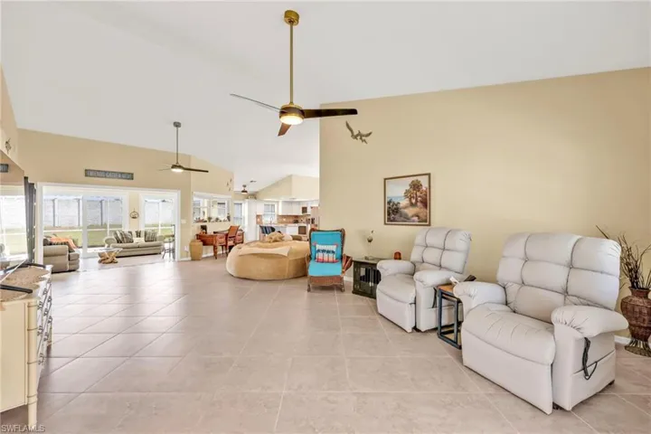 Living area featuring a ceiling fan, high vaulted ceiling, and light tile patterned floors
