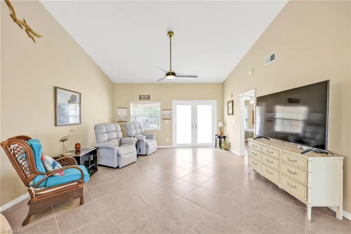 Living area featuring baseboards, french doors, visible vents, and ceiling fan