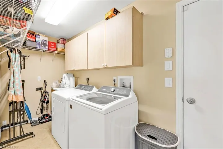 Laundry room with cabinet space, baseboards, light tile patterned floors, and washer and clothes dryer