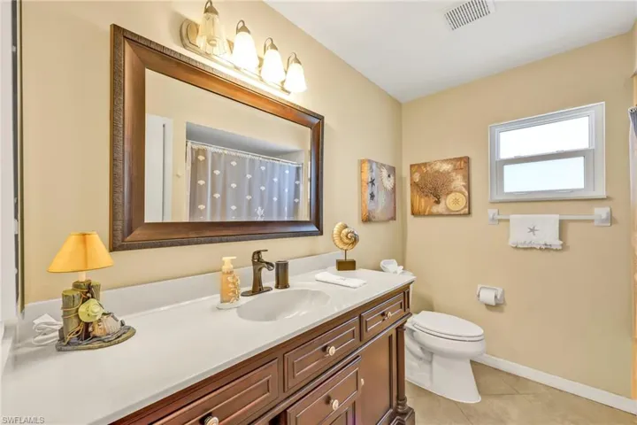 Bathroom featuring tile patterned floors, toilet, baseboards, visible vents, and vanity