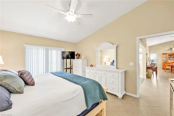 Bedroom featuring a ceiling fan, vaulted ceiling, light tile patterned flooring, and baseboards