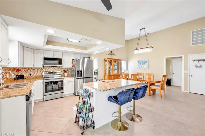 Kitchen with a sink, light tile patterned floors, white cabinetry, backsplash, and appliances with stainless steel finishes