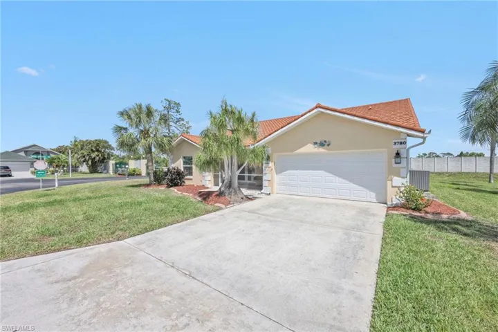 View of front of property featuring stucco siding, a front lawn, driveway, and a tiled roof