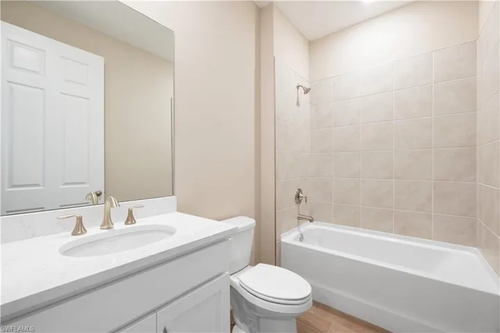 Full bathroom with vanity, tiled shower / bath, and toilet