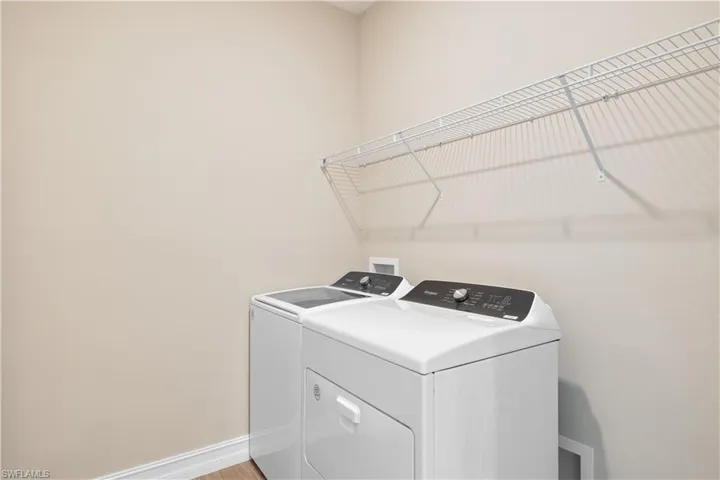Clothes washing area with light wood-type flooring and washer and dryer