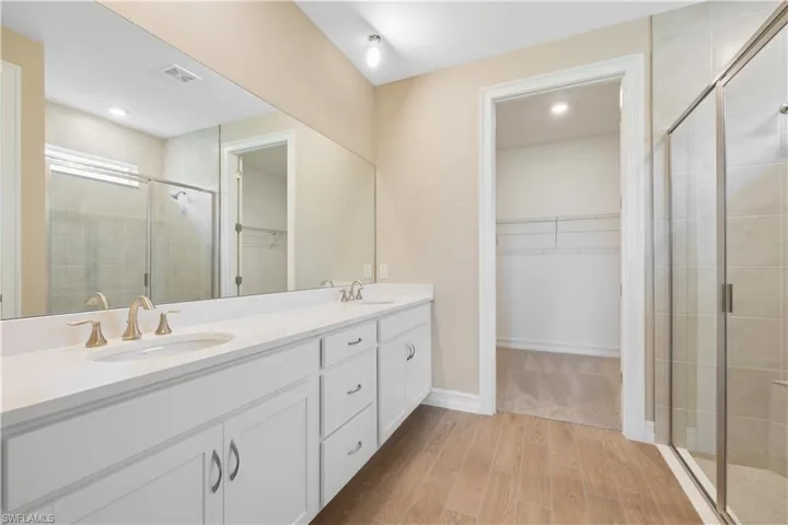 Bathroom featuring double vanity, walk in shower, and hardwood / wood-style floors
