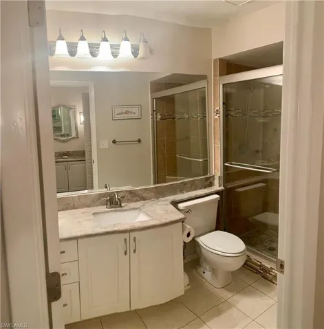 Master Bathroom with 2 separate sink areas. Tile patterned flooring, vanity, toilet, and a shower with shower door