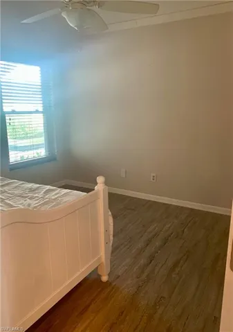 Main level guest bedroom featuring ceiling fan and dark hardwood / wood-style floors-- currently used as office