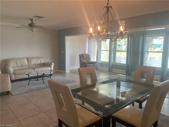 Living room and Dining area featuring a wealth of natural light, crown molding, and ceiling fan with notable chandelier