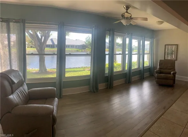 Sitting room with ceiling fan, plenty of natural light, a water view, and hardwood / wood-style floors