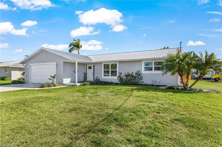 Single story home featuring stucco siding, a front lawn, and a garage