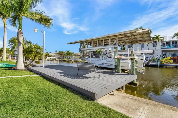 Dock area featuring a lawn, boat lift, and a water view