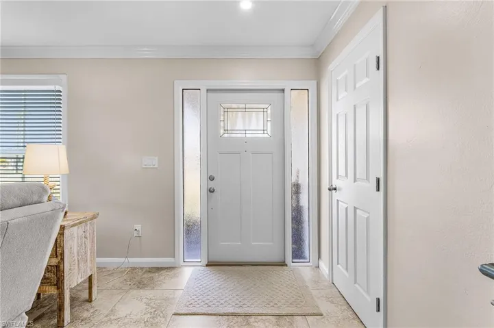 Foyer with crown molding and baseboards