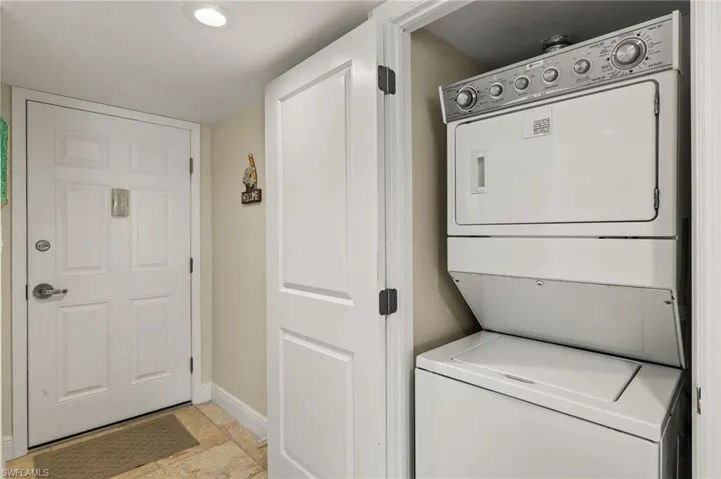 Washroom with baseboards and stacked washer / dryer