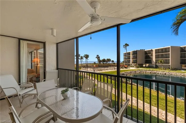 Balcony featuring outdoor dining area, a water view, and a ceiling fan