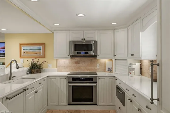 Kitchen featuring stainless steel appliances, white cabinetry, recessed lighting, a warming drawer, and decorative backsplash