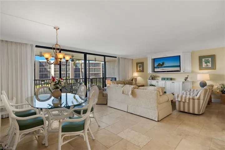 Living room with a chandelier, a wall of windows, and stone tile floors