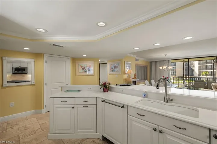 Kitchen with crown molding, white cabinetry, recessed lighting, light countertops, and a chandelier