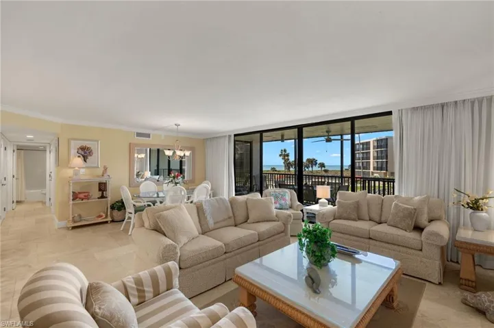 Living area with healthy amount of natural light, ornamental molding, and a chandelier