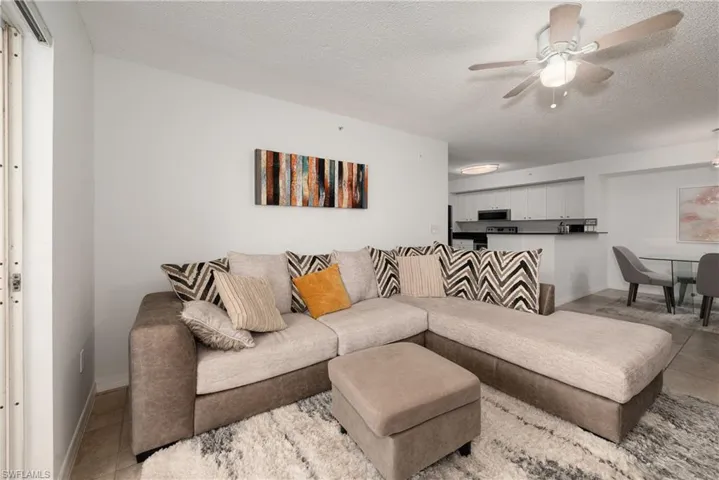 Living room with light tile patterned flooring, a ceiling fan, and a textured ceiling