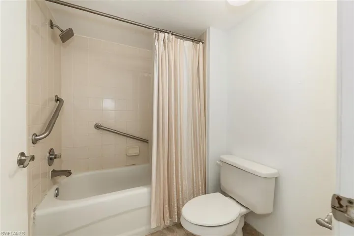 Bathroom with shower / bathtub combination with curtain and toilet