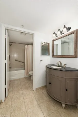 Bathroom with vanity, shower / bath combination with curtain, and light tile patterned flooring