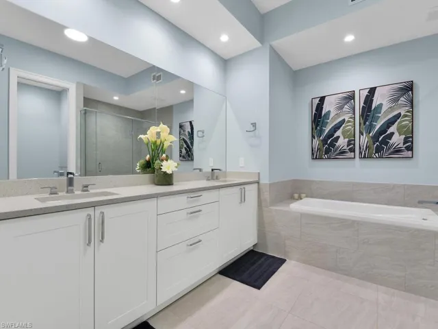 Bathroom with double vanity, a shower stall, a bath, light tile patterned flooring, and recessed lighting