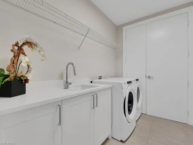 Laundry area with light tile patterned flooring, cabinet space, and washer and dryer