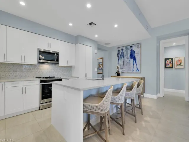 Kitchen with stainless steel appliances, a center island with sink, white cabinetry, and recessed lighting