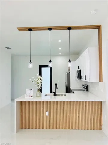 Kitchen island with wood-finish paneling, white countertop, and integrated sink with a black gooseneck faucet
