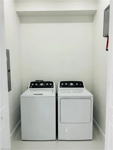 Dedicated laundry area with a white top-load washing machine and front-load dryer