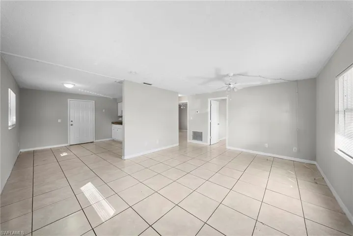 Empty room with healthy amount of natural light, ceiling fan, and light tile patterned flooring