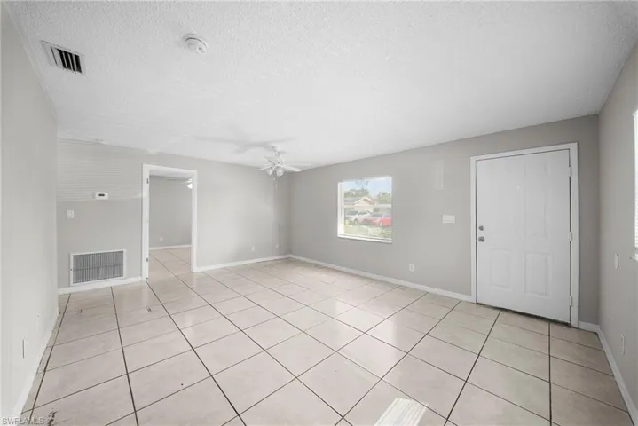 Spare room featuring a textured ceiling, ceiling fan, and light tile patterned flooring