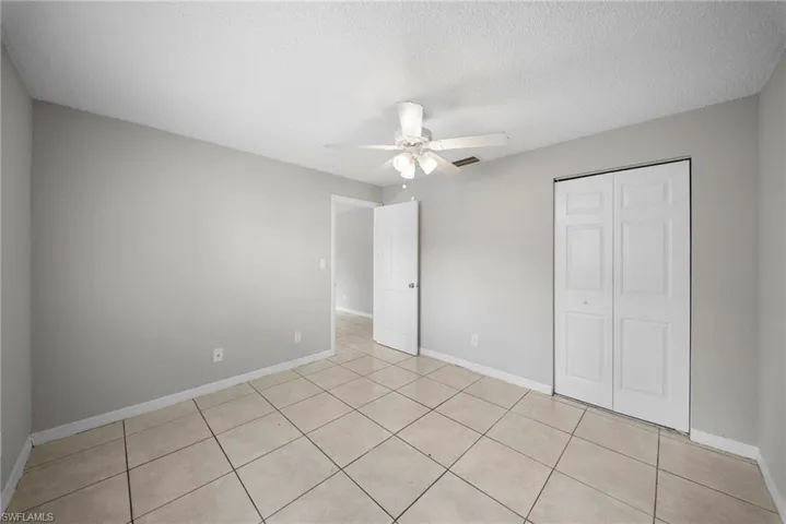 Unfurnished bedroom featuring a ceiling fan, a textured ceiling, a closet, and light tile patterned flooring