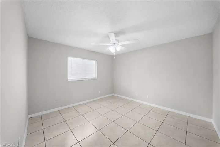 Empty room featuring a textured ceiling, a ceiling fan, and light tile patterned flooring
