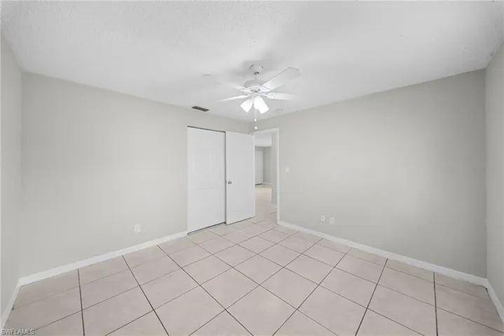 Unfurnished bedroom with a ceiling fan, a closet, a textured ceiling, and light tile patterned floors