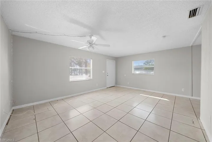 Spare room featuring a textured ceiling, light tile patterned flooring, and ceiling fan