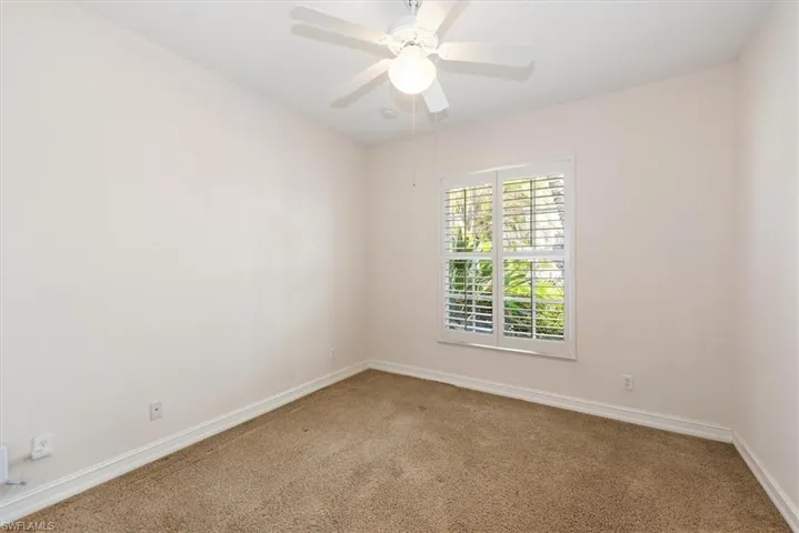Carpeted spare room featuring baseboards and ceiling fan