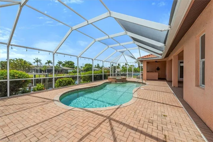 View of swimming pool with a patio area, a pool with connected hot tub, and glass enclosure