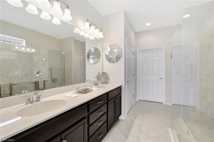 Full bath featuring double vanity, tile patterned floors, a sink, and tiled shower