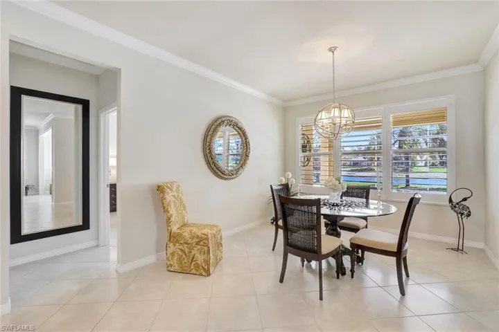 Dining space with an inviting chandelier, baseboards, light tile patterned floors, and ornamental molding