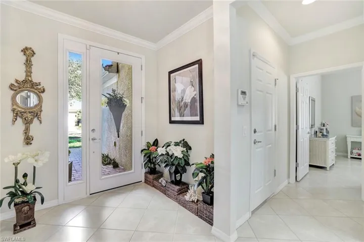 Foyer entrance with baseboards, crown molding, and light tile patterned flooring